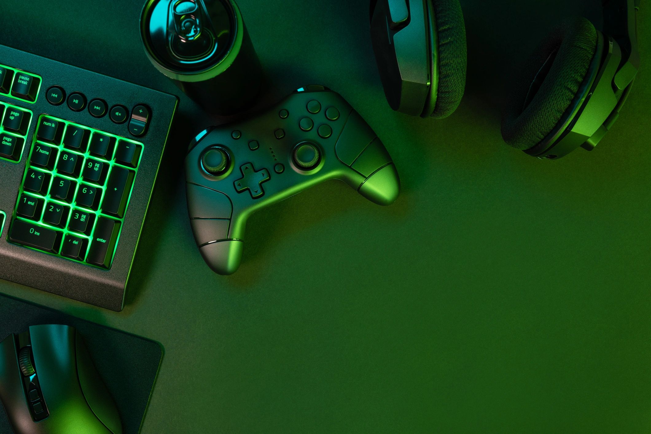 Green-lit keyboard and gaming gadgets on a black desk.