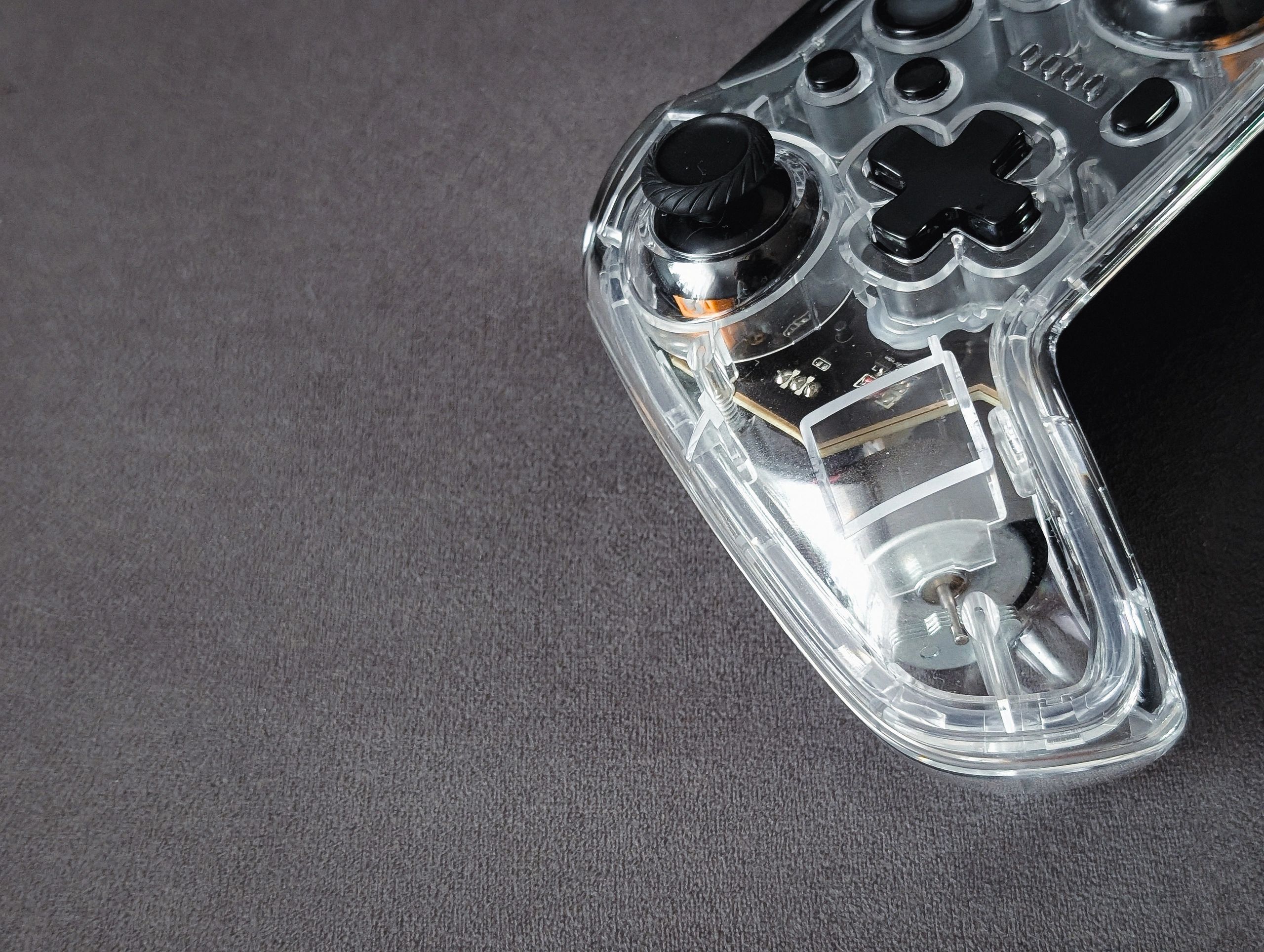 Transparent wireless game controller on dark background