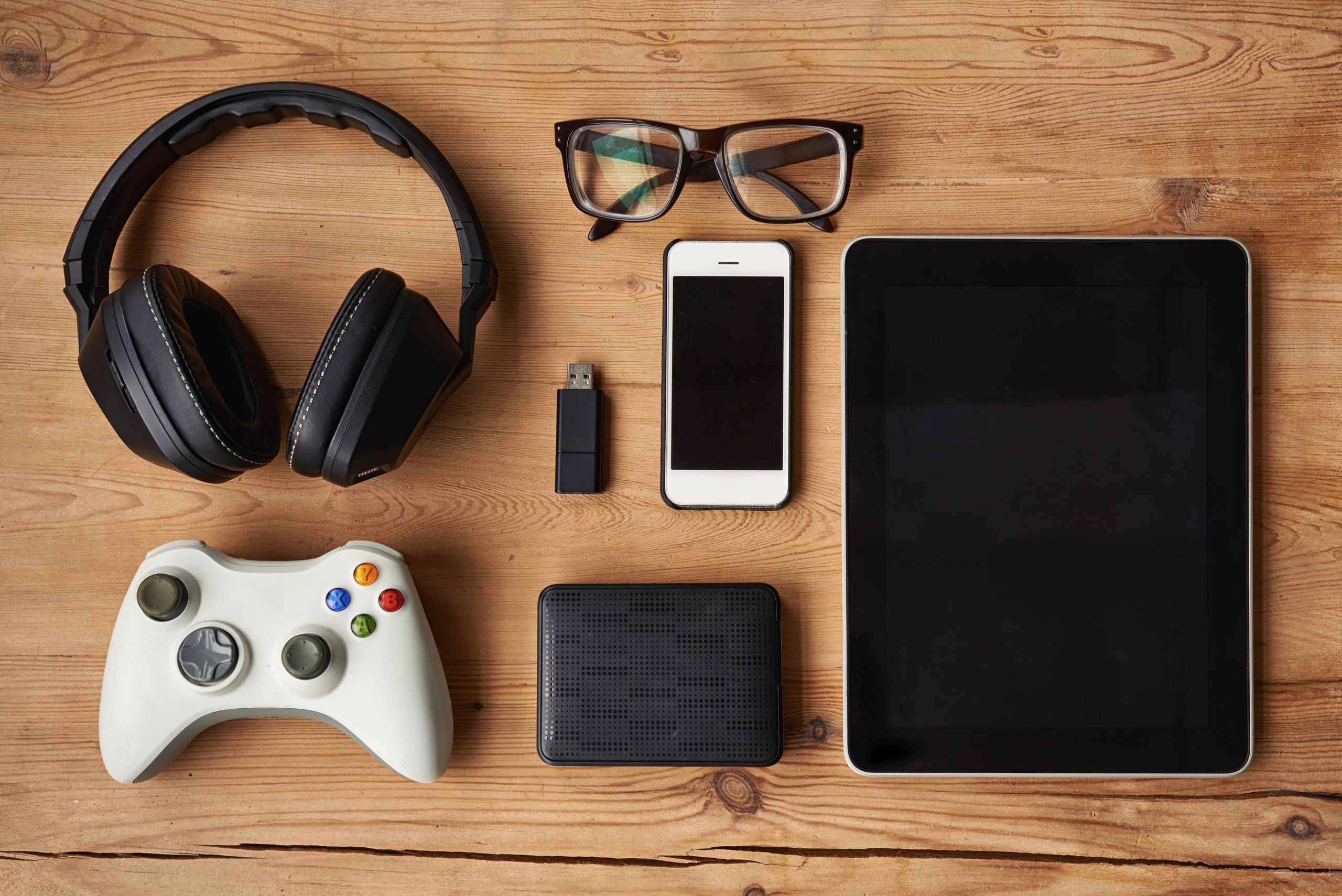 Gaming controller and tech accessories on a wooden table